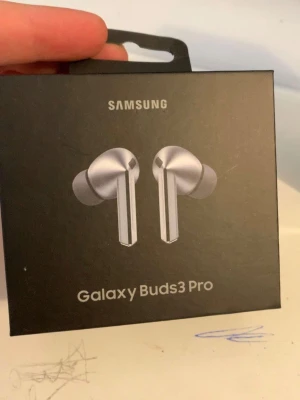 Samsung Galaxy Buds3 Pro hörlurar - Trådlösa in-ear hörlurar från Samsung, modell Galaxy Buds3 Pro. Snygg och modern design i silver med stilrena linjer och silikonproppar. Bluetooth-anslutning, adaptiv brusreducering och dynamisk LED. Perfekta för musik, samtal och gaming.