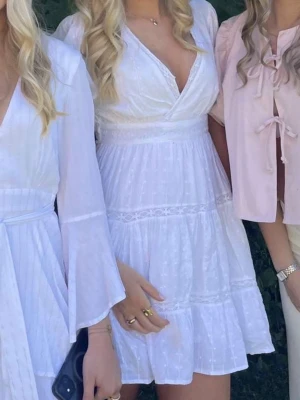 Vit klänning - Söt vit kortklänning från Zara med omlott och v-ringning. Klänningen har korta puffärmar, markerad midja och volangdetaljer i kjolen. Perfekt för sommarens alla tillfällen. Tillverkad i bomull för en luftig känsla.