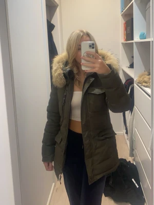Olivgrön parkajacka med pälskrage - Säljer en olivgrön vinterjacka från hollies med stor pälskrage på huvan. Jackan har flera fickor framtill och dragkedja med knappslå. Original pris ca 4000kr skriv privat för fler bilder🥰
