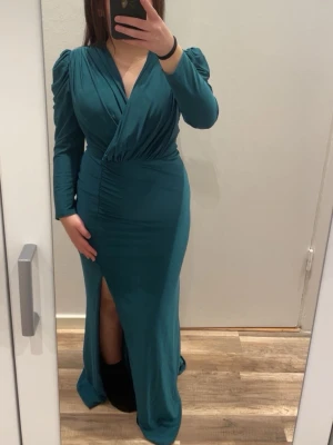 Elegant långklänning – perfekt för bal & bröllop - Säljer en jättefin långklänning i en elegant grön/teal färg som passar perfekt till bal, bröllop, studentfirande eller andra festliga tillfällen. Klänningen sitter jättefint på kroppen och ger en feminin och classy look. Har sytt den hos skräddaren och jag är 147 cm.   Den har: 	•	💚 Puffärmar som ger en trendig och elegant touch 	•	💚 Slits framtill för både stil och rörelsefrihet 	•	💚 Inbyggd BH, så du slipper tänka på extra underkläder 	•	💚 Smickrande V-ringning och draperad midja  