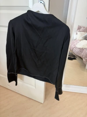 Svart topp - Snygg svart  topp med vita kontrastsömmar. Tröjan har långa ärmar och en avslappnad passform💗