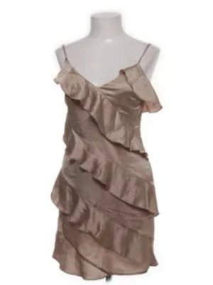  volangklänning  - Snygg kort klänning i champagnefärg från bohoo med tunna axelband och flera volanglager. Klänningen har en omlottliknande design upptill och är tillverkad i ett glansigt material som ger en lyxig känsla. Perfekt för dig som vill sticka ut. Aldrig använd