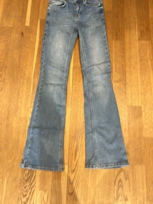 Blå bootcut jeans från Grunt - Säljer ett par blå  bootcut jeans från Grunt med gul kontrastsöm. Jeansen har utsvängda ben och är tillverkade i denim med snygg tvätt. Storlek 25