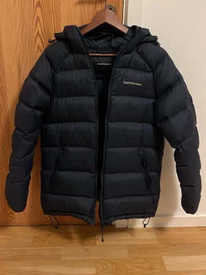Mörkblå dunjacka Peak Performance S - Säljer en mörkblå dunjacka från peak performance i storlek S!💕 Jackan är typ som ny eftersom jag knappt har använt den. Jackan har en puffig design, två sidofickor med dragkedja och justerbar nederkant. Perfekt för kalla vinterdagar. Köptes för 