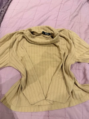 Beige ribbad polotröja Bik Bok - Beige ribbad polotröja från Bik Bok med lös passform och bred polokrage. Tröjan har långa ärmar och är tillverkad i ett mjukt, stretchigt material som känns skönt mot huden. Perfekt för lager på lager och enkel att styla.