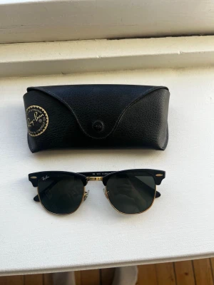 Ray-Ban Clubmaster solglasögon svart/guld - Snygga Ray-Ban Clubmaster solglasögon med svart ovandel och guldfärgade detaljer. Klassisk halvbågsform och mörka glas. Kommer med allt original. Säljer dem för att göra plats för nya 🕶️Priset kan rimligen diskuteras.