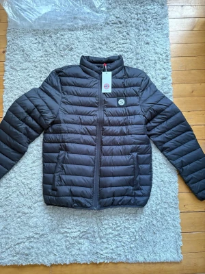 FC Bayern München svart dunjacka, storlek M - Nypris: 600kr Oanvänd med prislapp kvar och original förpackning. Från Fc Bayern Münchens officiella shop.  Svart dunjacka från FC Bayern München. Jackan har en hel dragkedja framtill och två sidofickor med dragkedja. FC Bayern München-logotypen finns på bröstet och i nacken.