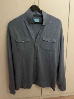 Blå cardigan från La Chemise - Stilren blå cardigan  från La Chemise med knäppning framtill och två bröstfickor med lock. Mjuk och tunn kvalitet, perfekt för lager på lager. Klassisk krage och långa ärmar ger en avslappnad men snygg look. Använd endast 2-3 gånger och är helt som ny, nypris 1500 mitt pris 550!