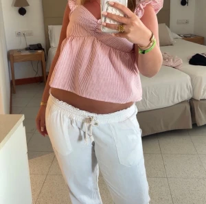 Vita linnebyxor från Roxy - Säljer ett par vita linnebyxor från Roxy med bred resår och dragsko i midjan. Byxorna har en avslappnad passform och är tillverkade i ett mjukt och luftigt material som känns skönt mot huden. Perfekta för en avslappnad och bekväm look. Köpta för 500kr.