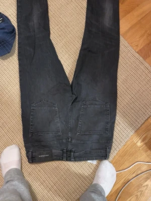 Svarta slim fit jeans  - Säljer ett par svarta slim fit jeans från Weekday med klassisk femficksdesign och knappgylf. Jeansen har raka ben och är tillverkade i stretchigt denimtyg för skön passform. Perfekta till en avslappnad streetwear-look.