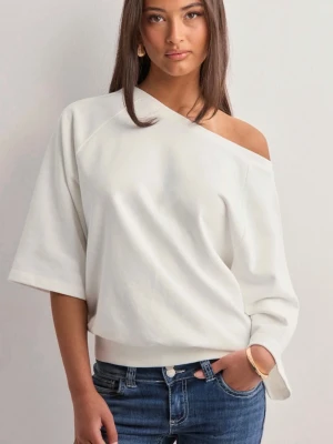 Vit offshoulder topp - Trendig vit offshoulder topp med lös passform och bred ribbad kant nedtill. Toppen har halvlånga ärmar och en avslappnad siluett som ger en cool och modern vibe. Perfekt att styla med jeans eller kjol för en snygg look.