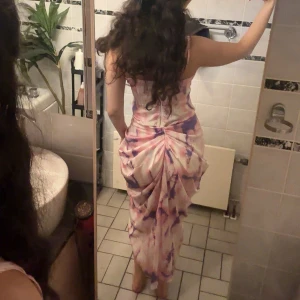 Somrigt set kjol och topp - Säljer ett superfin set med smala axelband och draperad midja. Settet har ett unikt mönster i rosa, lila och vitt med coola tie-dye vibes. Figurnära passform och snyggt fall. Perfekt för dig som vill sticka ut med en färgglad och trendig look. Det är inte en klänning, utan topp och kjol. Säljer för toppen är lite stor för mig