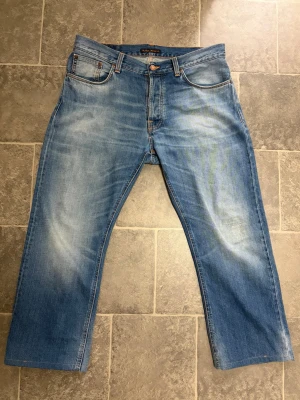Nudie Jeans - Ett par riktigt feta nudie jeans som har en snygg stentvätt! Dom är orginallt 30 i längd men nu är dom kanske 29 eftersom de är upplagda ett par cm, innerbenslångden är 69cm och hela jeansen är 96-97cm. Dom har lite slitningar vid ena knäet men det är inget som märks av! Om du vill ha fler mått är det bara att skriva!