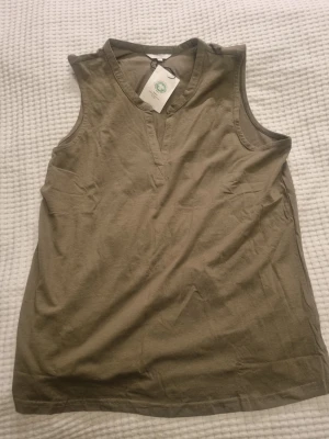 Grön ärmlös topp Cellbes - Grön ärmlös topp från Cellbes med v-ringad hals och enkel design. Tillverkad i mjuk bomull som känns skön mot huden. Perfekt för varma dagar och enkel att matcha med olika stilar.