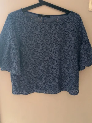 Blå spetsblus från Reserved - Säljer en blå blus från Reserved med vackert spetsmönster och vida trekvartsärmar. Blusen har rund halsringning och är perfekt för dig som gillar romantiska detaljer. Superfin att styla till både jeans och kjol!