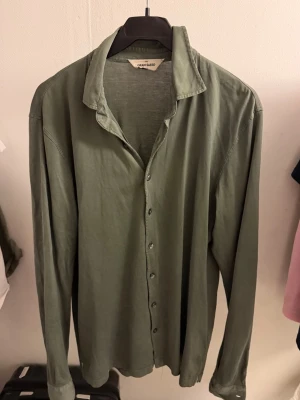 Gran Sasso skjorta limited edition  - Säljer en stilren limited edition grön skjorta från Gran Sasso med klassisk krage och knappar framtill. Skjortan är långärmad och har en relaxed fit som passar perfekt till olika outfits. Materialet är mjukt och känns bekvämt mot huden.