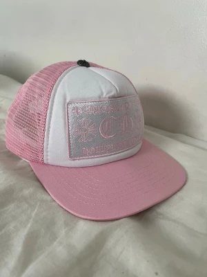 Rosa och vit keps från Chrome Hearts - Säljer min jätte fina keps ifrån Chrome Hearts den är perfekt inför sommaren och soliga dagar, riktigt sällsynt och unik rosa o vit färg! Kepsen är justerbar/onesize, pris går självklart diskutera!