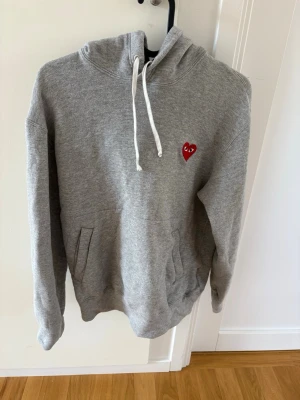 Grå hoodie Comme des Garçons Play - Comme des Garçons PLAY hoodie i grå färg, storlek S.  Passar folk från cirka 165 till 175 cm. Använt denna hoodie några fåtal gånger men har för det mesta bara tagit upp plats i garderoben. Nypris: 2500kr  mitt pris: 1299 