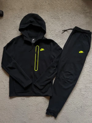 Svart Nike Tech  - Svart/neon gul Nike tech tracksuit i storlek S. Köpt för några år sedan från Footlocker, men tracksuiten är i bra skick. För mer frågor eller bilder är det bara att skriva! 