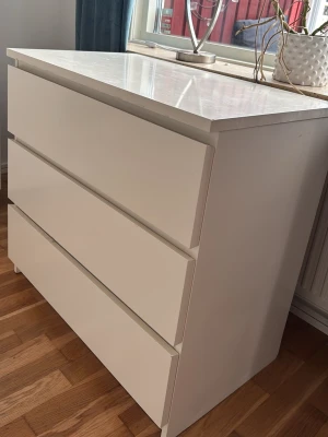 Vit byrå med tre lådor - HÄMTA SJÄLV! Prisförhandlig. Snygg och stilren vit byrå med tre stora lådor. Byrån har en modern, minimalistisk design med släta fronter utan handtag och är tillverkad i trä eller träkomposit. Perfekt för förvaring i sovrum eller hall och passar in i de flesta inredningsstilar. Lite ful på toppen men går o lösa innan säljs
