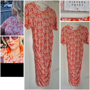 Blommig klänning från Sisters Point - Underbar småblommig klänning från Sisters Point i vitt, rött och orange. Modellen är midilång med korta ärmar och har rynkade detaljer längs sidorna. Sitter så fint pch smickrande. Tunn och skön utan att vara genomskinlig. Perfekt för sommarens alla tillfällen!