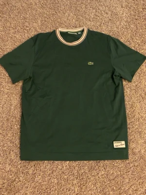 Grön t-shirt från Lacoste - Snygg grön t-shirt från Lacoste i storlek M. T-shirten är i topp skick då jag aldrig använt den eftersom den var för stor för mig. Nypris 1200kr