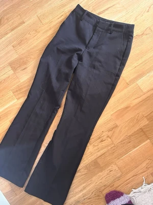 Svarta kostymbyxor från BikBok - Snygga svarta kostymbyxor från BikBok med klassisk rak passform och pressveck. Byxorna har hällor för skärp och är tillverkade i ett slätt tyg som ger en stilren look. Perfekta för dig som gillar en clean och tidlös stil.