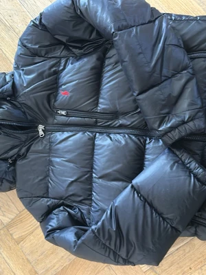 Svart pufferjacka från Polo Ralph Lauren - Svart pufferjacka från Polo Ralph Lauren med diskret röd logga på bröstet och tvåvägsdragkedja. Jackan har quiltad design och är vadderad för extra värme. Perfekt för kalla vinterdagar och har en sportig, stilren look. PRIS KAN DISKUTERAS 