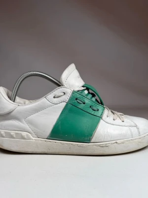 Valentino Garavani ”Open” Sneakers – Vit/Grön – Stl 43.5 (EU) / 42.5 (IT) - Säljer mina klassiska Valentino Open Sneakers i vitt läder med det snygga gröna bandet. En riktig lyxsneaker som passar till allt! 