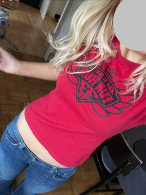 Röd croppad t-shirt från Diesel - Säljer en röd croppad t-shirt från Diesel med svart tryck framtill. T-shirten har korta ärmar och en tight passform som framhäver midjan. Perfekt för dig som gillar streetwear och vill ha en cool och enkel topp till jeans eller kjol.