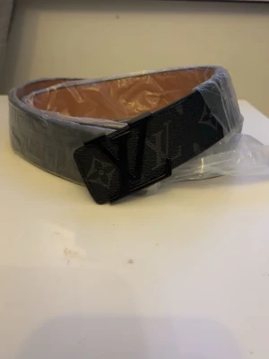 Svart designer bälte  - Svart designer bälte med mönster och svart buckla. Inplastad och helt oanvänd, passar perfekt med en stilig outfit.