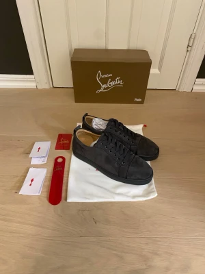 Grå sneakers från Christian Louboutin - Stilrena grå sneakers från Christian Louboutin i mocka med klassisk låg siluett. Skorna har grå skosnören, diskret logga på insidan och levereras med originalkartong, dustbag och tillbehör. Perfekta för dig som gillar exklusiva detaljer och lyxig känsla.