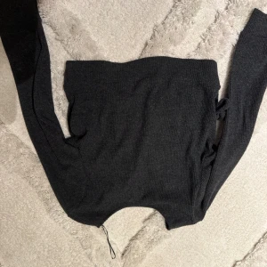 Svart omlottkofta med knytband - Snygg svart omlottkofta med långa ärmar och knytband i sidan. Koftan har en croppad passform och är tillverkad i ett mjukt, ribbat material som ger en skön känsla. Perfekt att styla över ett linne eller t-shirt för en trendig look.