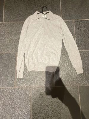 Kashmir quatre-zip med krage från John Henric  - En stilren ljusgrå kashmirtröja med krage och kort dragkedja framtill.