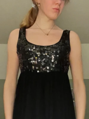 Cocktail klänning-PARIS KATE AND I - Säljer en snygg cocktail klänning som påminner om Serena i GG. Klänningen är svart, har fina silvriga paljetter längs bysten och ballongslut. Längd:85 cm, storlek S. 