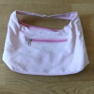 Söt Axelväska - Jättesöt axelväska som har 2 små defekter. Den har en liten brun fläck längst ner(inget man tänker på) och en liten del av dragkedjan har gått av men den funkar enkelt att stänga och öppna ändå. Den har två fack och man får plats med mycket. Hör av er om frågor!❤️(Säljer även på Vinted ifall man skulle vilja köpa där)