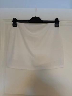 Vit kortkjol i enkel design - Säljer en vit kortkjol med rak passform. Kjolen är enfärgad och har ”inbyggda” shorts. Mjukt material och fint skick! Storlek L men väldigt liten i storlek så passar mig som har S/M🤗