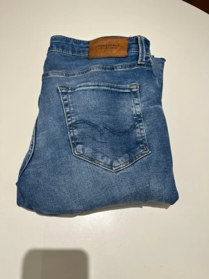 Ljusblå slim fit jeans Jack & Jones - Snygga ljusblå jeans från Jack & Jones i slim fit-modell. Klassisk femficksdesign med läderpatch bak i midjan. Jeansen har en lätt tvättad look och är tillverkade i bomull med lite stretch för extra komfort. Modellen är 187 och väger 70 kg. Vid minsta fundering är det bara att skriva!