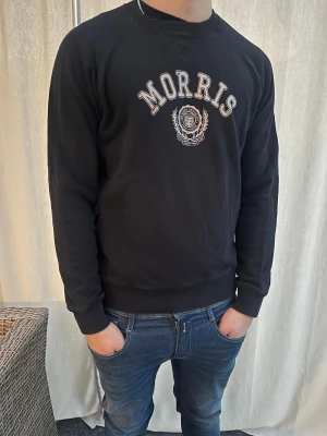 Marinblå sweatshirt från Morris, storlek L - Svart sweatshirt från Morris i storlek L men passar även M, jag själv på bilden är 184 cm. Tröjan har rund hals, ribbade muddar och är tillverkad i mjuk bomull. 