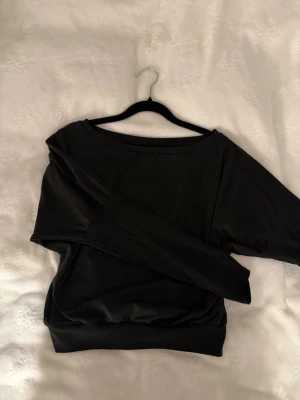 Svart off shoulder med tumhål - Säljer en svart hoodie i mjukt material med bred mudd i midjan och tumhål på ärmarna. 