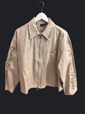 Sumwon zip - Sumwon zip-jacka i beige. Broderad text på ärmar och krage. Riktigt clean och unik modell. Bra skick. Skickas eller möts upp.