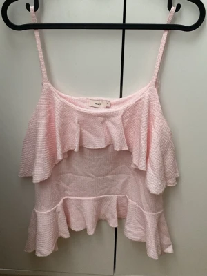 Ljusrosa volangtop från Nelly - Aldrig använd topp ifrån Nelly, Supersöt ljusrosa linnetopp med tunna axelband och dubbla volangdetaljer både upptill och nedtill. Toppen är ärmlös och har en luftig, croppad passform som passar perfekt till sommaren.  Ordiranie pris : 249