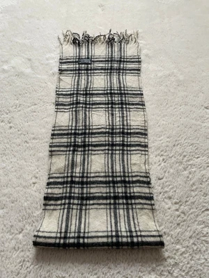 Burberry Halsduk - En vit halsduk från burberry med svarta rutor 🧣 | Halsduken är gjord av 100% lamm ull och är i väldigt bra skick - 9/10. ✅ | Inget og är inkluderat i priset. | Halsduken är 140cm lång 📏| Priset är inte hugget i sten - Hör av er vid minsta fundering 🙌