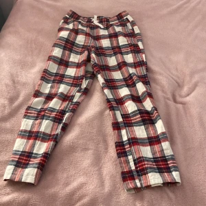 Rutiga pyjamasbyxor från Kappahl - Säljer ett par mysiga pyjamasbyxor från Kappahl i rött, vitt, grönt och blått rutigt mönster. Byxorna har resår i midjan och är gjorda i mjukt bomullstyg, perfekta för chillkvällar hemma.