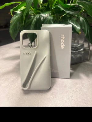 Grått Rhode mobilskal i silikon - Snyggt och stilrent mobilskal från Rhode i ljusgrått silikon. Skalet har en unik 3D-design på baksidan och ett rutmönster på insidan för extra stötdämpning. Passar perfekt för dig som vill ha ett modernt och skyddande skal till din mobil.