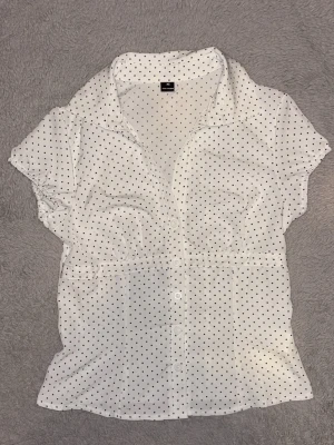Prickig skjorta/blus - Jättesöt kortärmad skjorta med insydd midja och prickigt mönster. Har bara använt 1 gång och säljer pga att den är lite för stor på mig i bysten