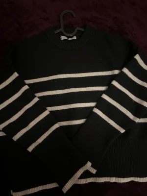 Svartvit randig stickad tröja Bershka - Svart stickad tröja från Bershka med vita horisontella ränder. Tröjan har rund halsringning, långa ärmar och ribbade muddar vid ärmslut och nederkant. Perfekt för en chill och stilren look.