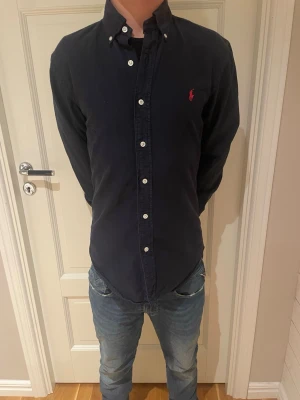 Mörkblå skjorta från Ralph Lauren - Säljer en mörkblå skjorta från Ralph Lauren i slim fit-modell. Inga smutsfläckar eller hål i skjortan.  Kan gå ner lite vid snabb affär nypris är upp mot 1500+.
