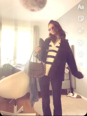 Randig stickad tröja med v-ringning - Snygg stickad tröja med breda marinblå och vita ränder, v-ringad krage och ribbade muddar. Perfekt för en avslappnad och trendig look. Materialet är mjukt och bekvämt, och tröjan har en lite oversized passform.