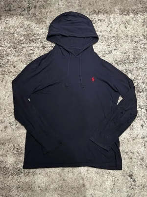 Ralph Lauren hoodie - En riktigt schysst tunn hoodie från Ralph Lauren i ett rätt bra skick! Den har inga synliga skavanker förutom den halvt bortskrapade nackloggan! Den är i storlek M och har mycket mer att ge!👌.    100% Bomull.                                                          Tveka inte på att skriva ifall du är i behov av fler bilder på plagget eller mått! 📸📏 Skriv vid minsta lilla fundering då jag oftast svarar fort! 💬 Fraktar alltid samma dag eller dagen efter beställning! 🚛